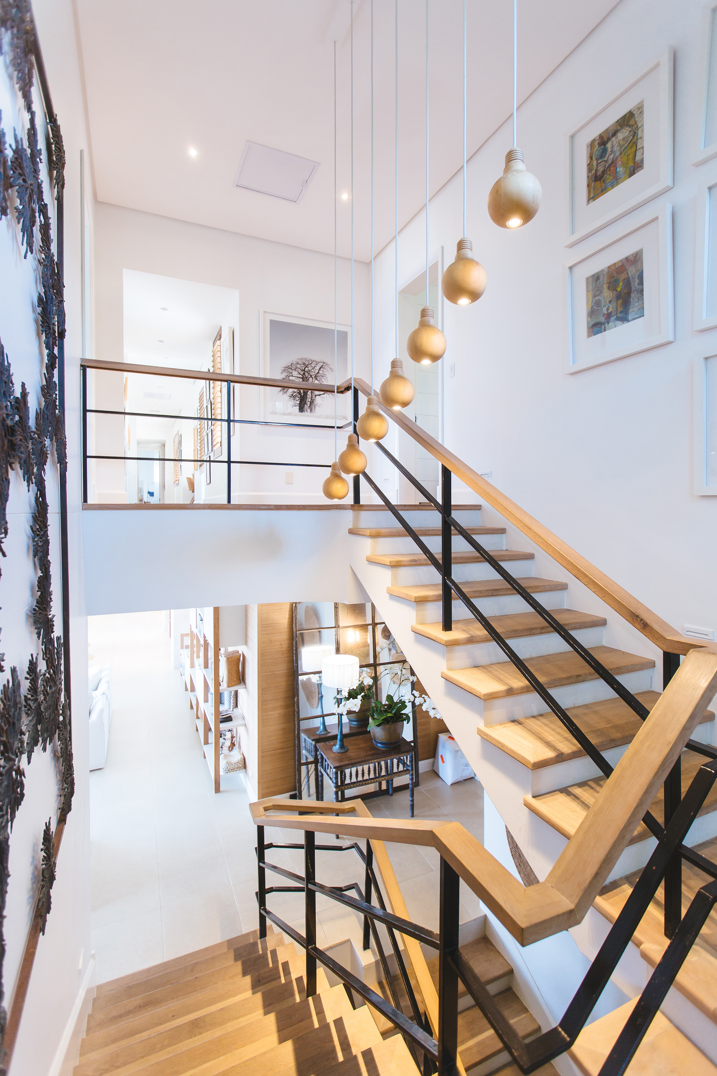 Modern wooden stairwell with pictures on the walls & lovely lighting.